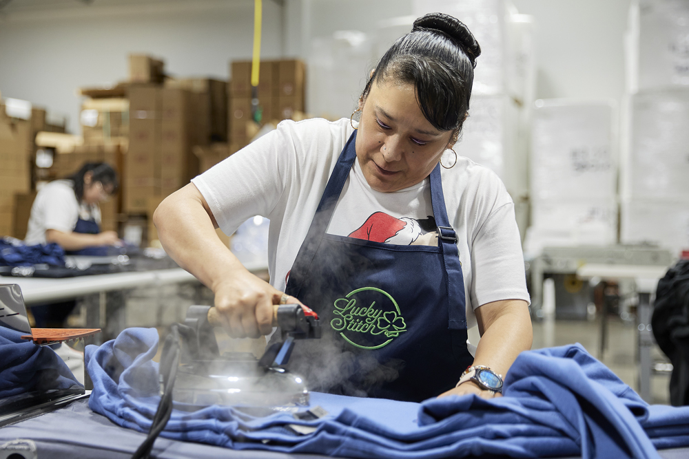 Employee finishing a customized sweatshirt at LuckyStitch